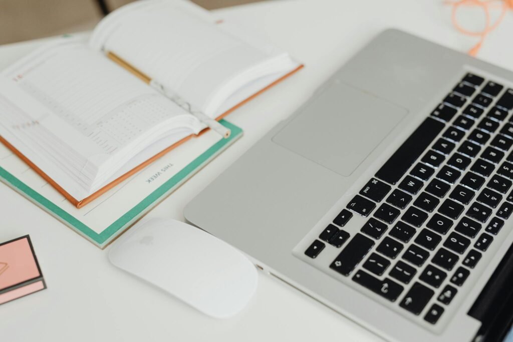 Overhead view of a modern workspace featuring an open planner and laptop on a tidy desk.